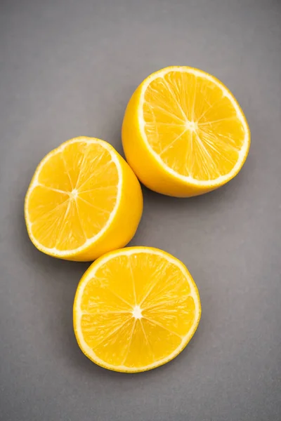 Вид зверху на три половини соковитих лимонів на сірому фоні — стокове фото