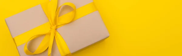 Trop vue du présent enveloppé avec ruban sur l'arc isolé sur jaune, bannière — Photo de stock