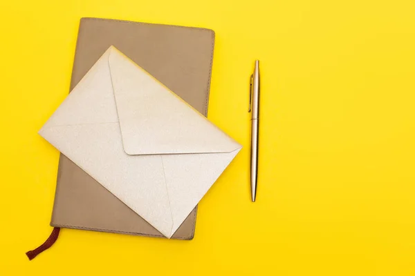 Top view of envelope on notebook near pen isolated on yellow — Stock Photo