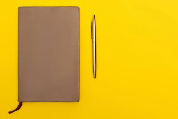 Ansicht des Kopierbuchs in der Nähe des goldenen Stifts isoliert auf gelb — Stockfoto