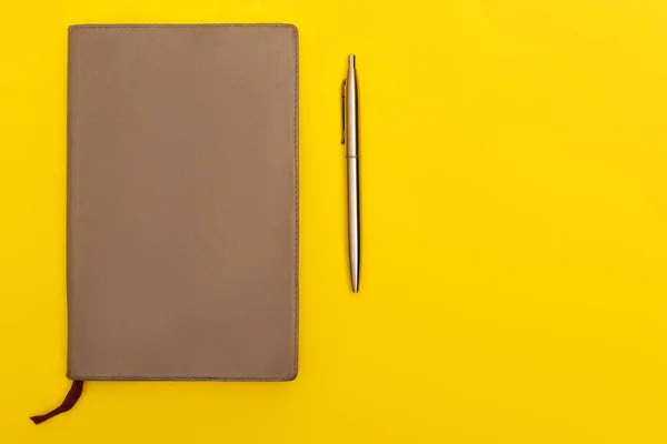 Top view of copy book near golden pen isolated on yellow — Stock Photo