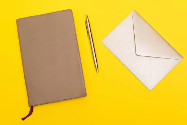 Vista superior do envelope perto do livro da cópia e da pena dourada isolados no amarelo — Fotografia de Stock