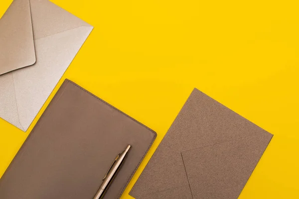 Vista superior de notebook com caneta dourada perto de envelopes isolados em amarelo — Fotografia de Stock