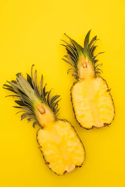 Vue de dessus de moitiés d'ananas mûrs et sucrés isolés sur jaune — Photo de stock