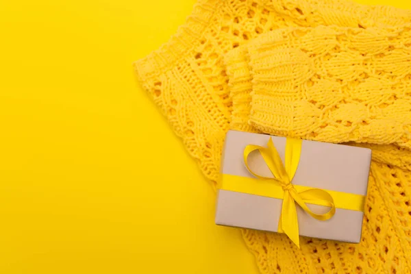 Top view of wrapped present near knitted jumper isolated on yellow — Stock Photo