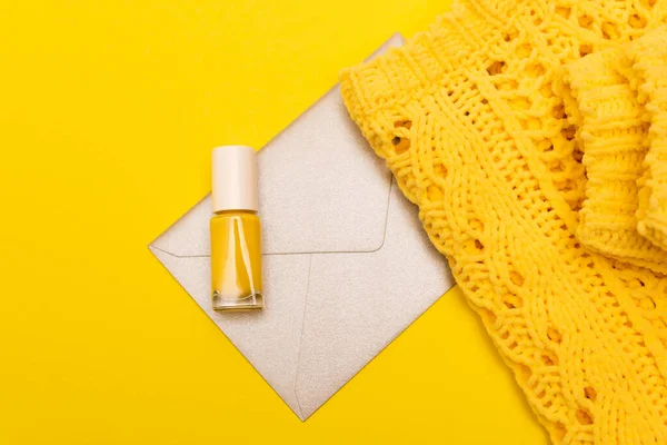 Vista superior de la botella con esmalte de uñas, cerca de la ropa y el sobre aislado en amarillo - foto de stock