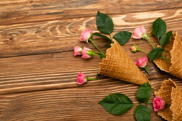 Vue de dessus des fleurs roses dans les cônes de gaufre sur la surface en bois — Photo de stock