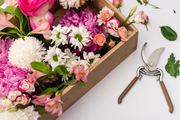 Hand pruners near wooden box with blooming flowers on white — Stock Photo