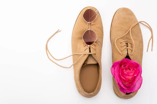 Vue du dessus de la fleur rose et des lunettes de soleil sur les chaussures masculines isolées sur blanc — Photo de stock