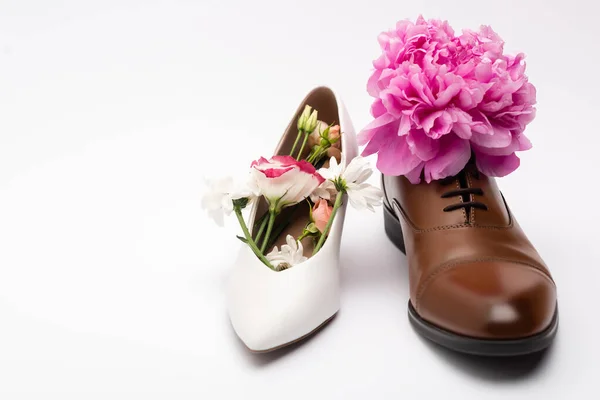 Pink flower in male shoe near female footwear on white — Stock Photo
