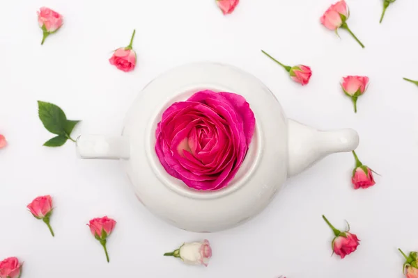 Vista dall'alto di fiore rosa in teiera di porcellana vicino a rose di tè su bianco — Foto stock