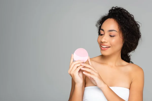 Mujer afroamericana sonriente sosteniendo limpiador de silicona aislado en gris — Stock Photo