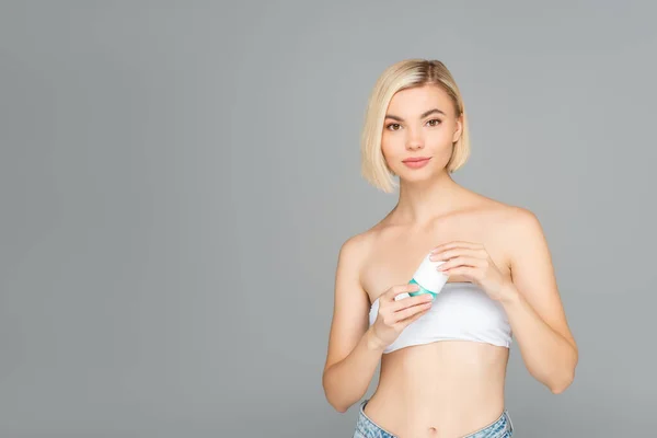 Blonde woman holding deodorant isolated on grey — Stock Photo