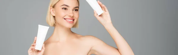 Jeune femme avec des tubes de maintien de la peau propre avec mousse nettoyante isolée sur gris, bannière — Photo de stock