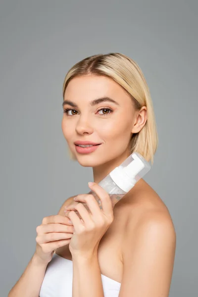 Young woman with clean skin looking at camera while holding cleansing foam isolated on grey — Stock Photo