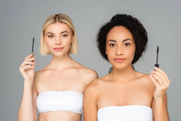 Multiethnische Frauen halten Applikatoren für Wimperntusche isoliert auf grau — Stockfoto