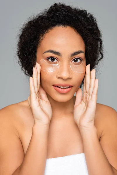 Femme afro-américaine avec une peau parfaite appliquant des patchs pour les yeux isolés sur gris — Photo de stock