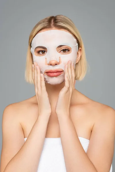 Blonde woman in face sheet mask isolated on grey — Stock Photo