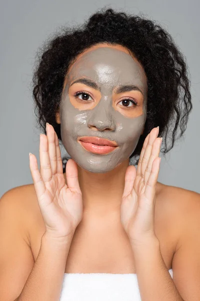 Afroamerikanerin mit Lehmmaske blickt isoliert auf graue Kamera — Stockfoto