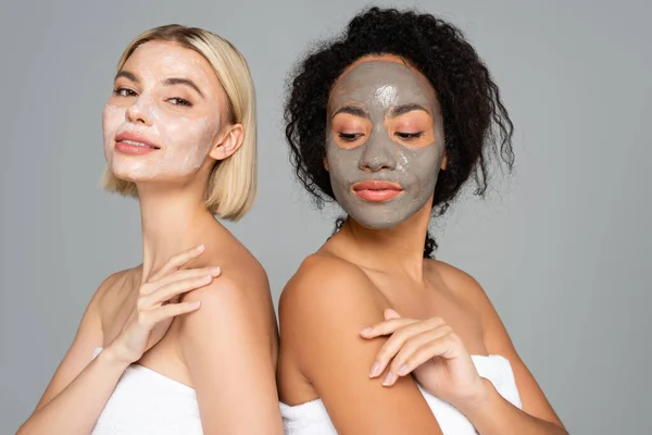 Multiethnic women in  facial masks standing isolated on grey — Stock Photo