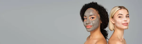 Multiethnische Frauen mit nackten Schultern und Gesichtsmasken, die vereinzelt auf grauem Banner in die Kamera schauen — Stockfoto