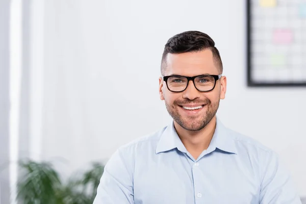 Homem de negócios feliz em óculos sorrindo enquanto olha para a câmera — Fotografia de Stock