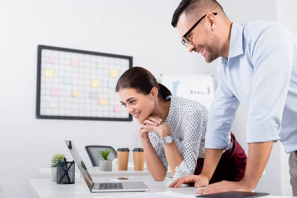 Zufriedene Geschäftsleute schauen auf Laptop auf Schreibtisch — Stockfoto