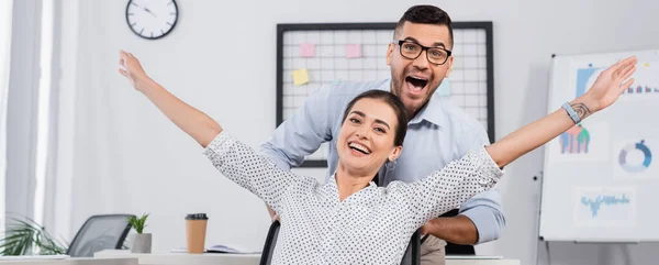 Excited businessman behind amazed businesswoman with outstretched hands, banner — Stock Photo