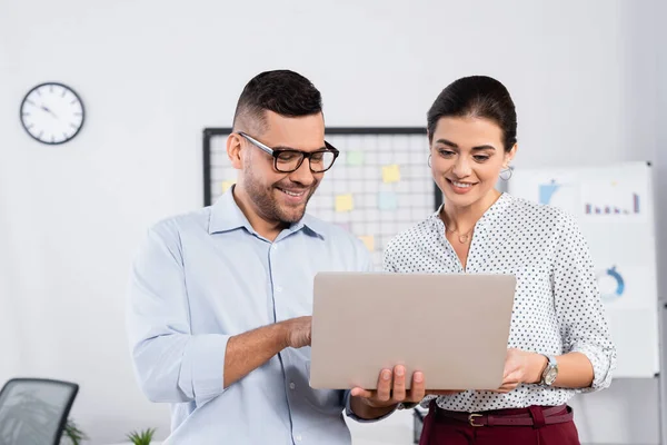 Geschäftsleute schauen im Büro lächelnd auf Laptop — Stockfoto