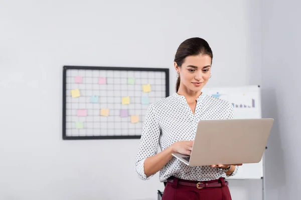 Positive Geschäftsfrau mit Blick auf Laptop im Büro — Stockfoto