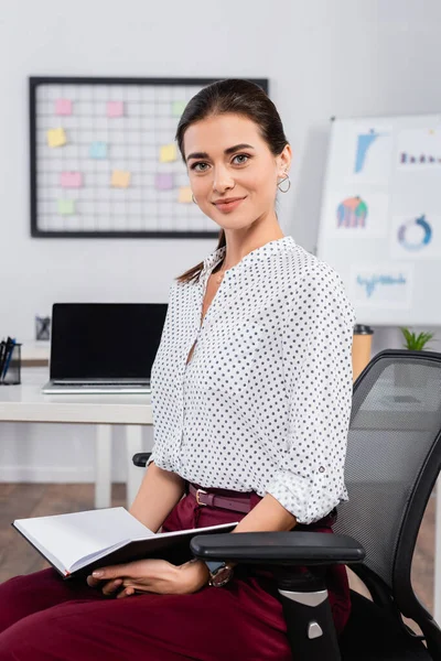 Femme d'affaires heureuse assise sur une chaise avec ordinateur portable — Photo de stock