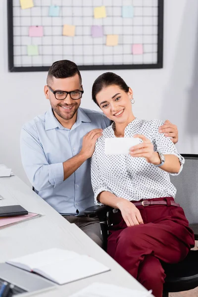 Happy businesswoman taking selfie with coworker in glasses — Stock Photo