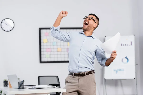 Amazed businessman in glasses holding document in office — Stock Photo