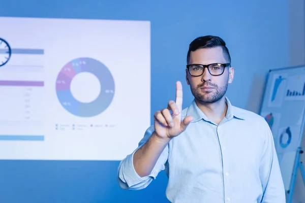 Бізнесмен в окулярах, вказуючи пальцем поблизу діаграм і графіків — стокове фото