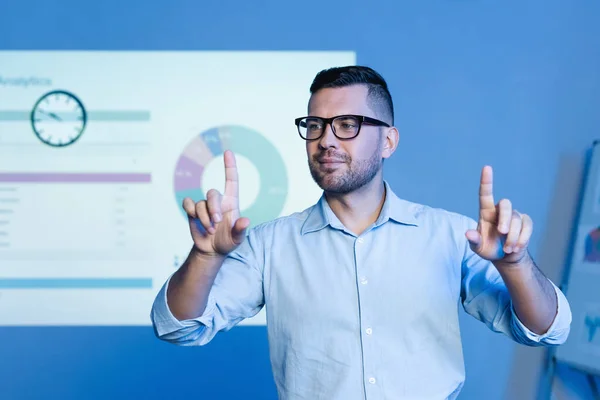 Geschäftsmann mit Brille zeigt mit Fingern in die Nähe von Diagrammen und Grafiken an der Wand — Stockfoto