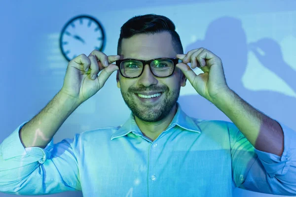 Homme d'affaires heureux ajustant des lunettes et souriant au bureau — Photo de stock