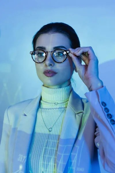 Empresária em terno ajustando óculos e olhando para longe no escritório — Fotografia de Stock