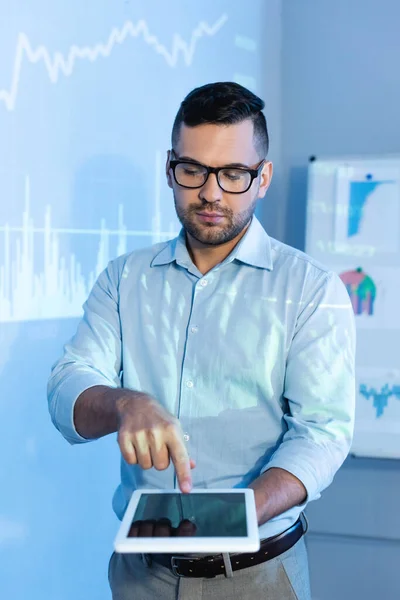 Uomo d'affari in occhiali che punta con il dito al tablet digitale con schermo bianco — Foto stock
