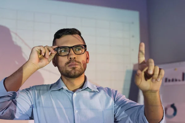 Businessman in glasses pointing with finger on blurred foreground — Stock Photo