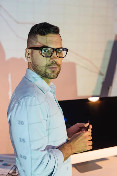 Businessman in glasses holding pen and looking at camera — Stock Photo