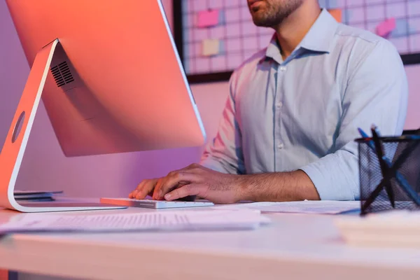 Vista recortada del hombre de negocios escribiendo en el teclado de la computadora cerca del monitor - foto de stock
