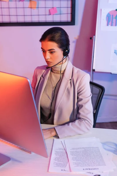 Operatore femminile in auricolare guardando il monitor del computer in ufficio — Foto stock