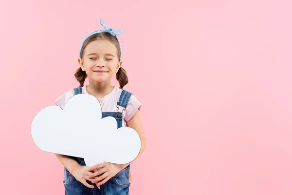 Pleased kid with closed eyes holding thought bubble isolated on pink — Stock Photo
