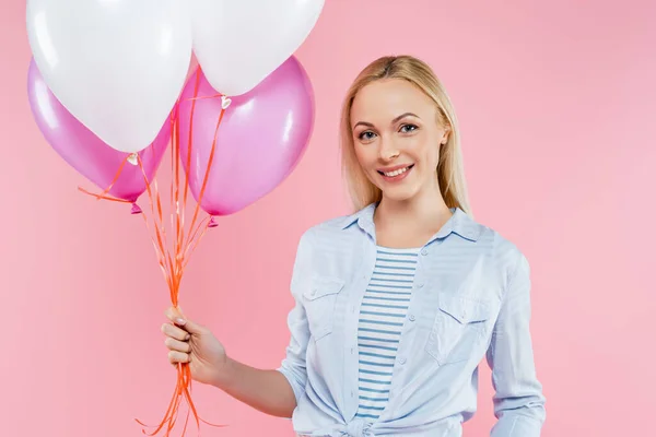 Donna felice in piedi e tenendo i palloncini isolati su rosa — Foto stock