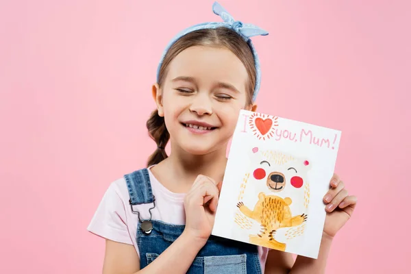 Glückliches Kind hält Grußkarte mit Ich liebe dich Mama Schriftzug isoliert auf rosa — Stockfoto