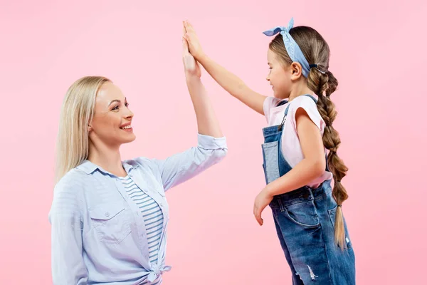 Glückliche Mutter schenkt lächelnder Tochter High Five auf rosa — Stockfoto