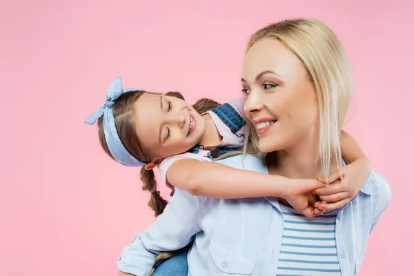 Fröhliches Kind umarmt glückliche Mutter isoliert auf rosa — Stockfoto