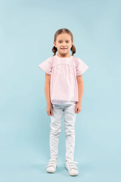 Full length of cheerful child standing on blue — Stock Photo