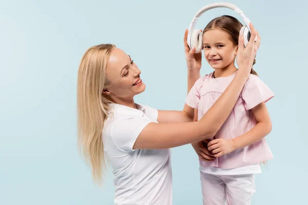 Happy mother wearing wireless headphones isolated on blue — Stock Photo