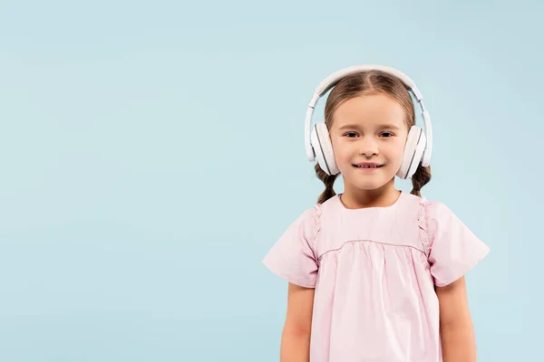 Happy kid in wireless headphones smiling isolated on blue — Stock Photo